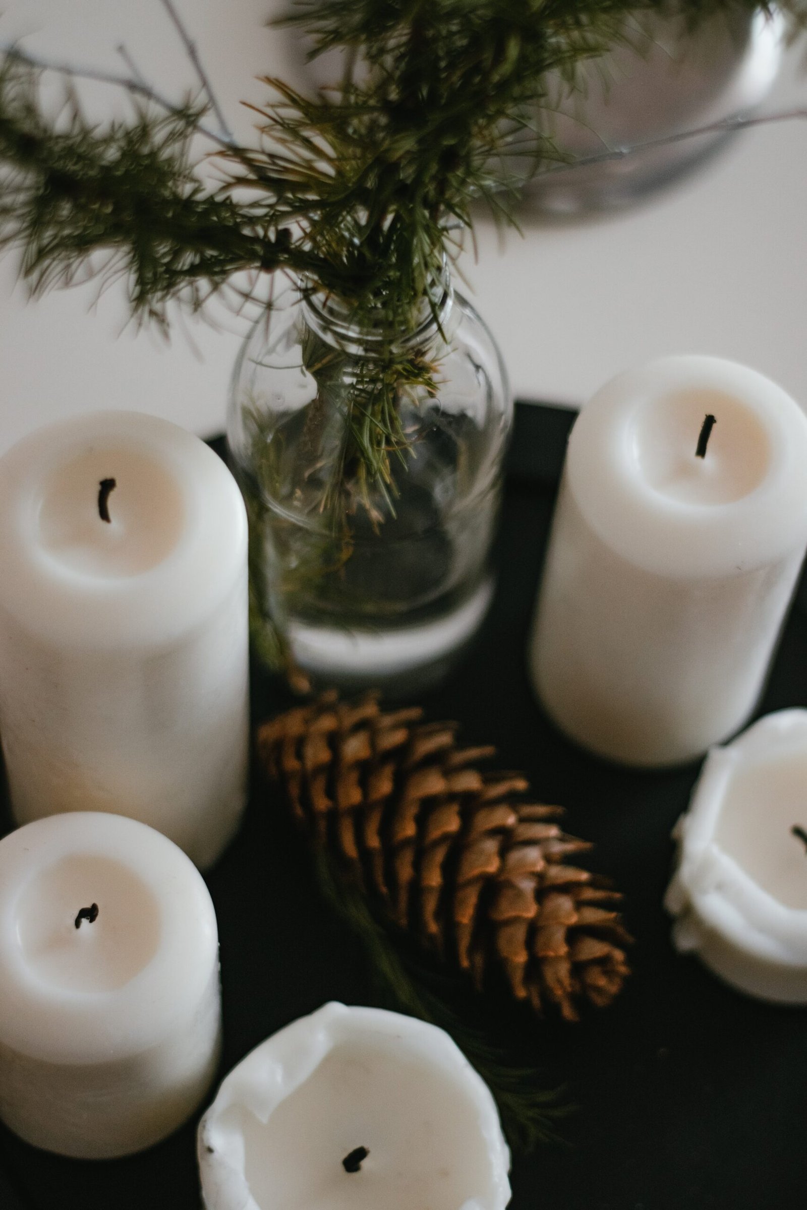 white pillar candle beside brown pine cone