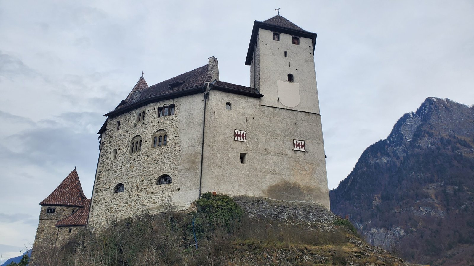 a castle on a hill with mountains in the background