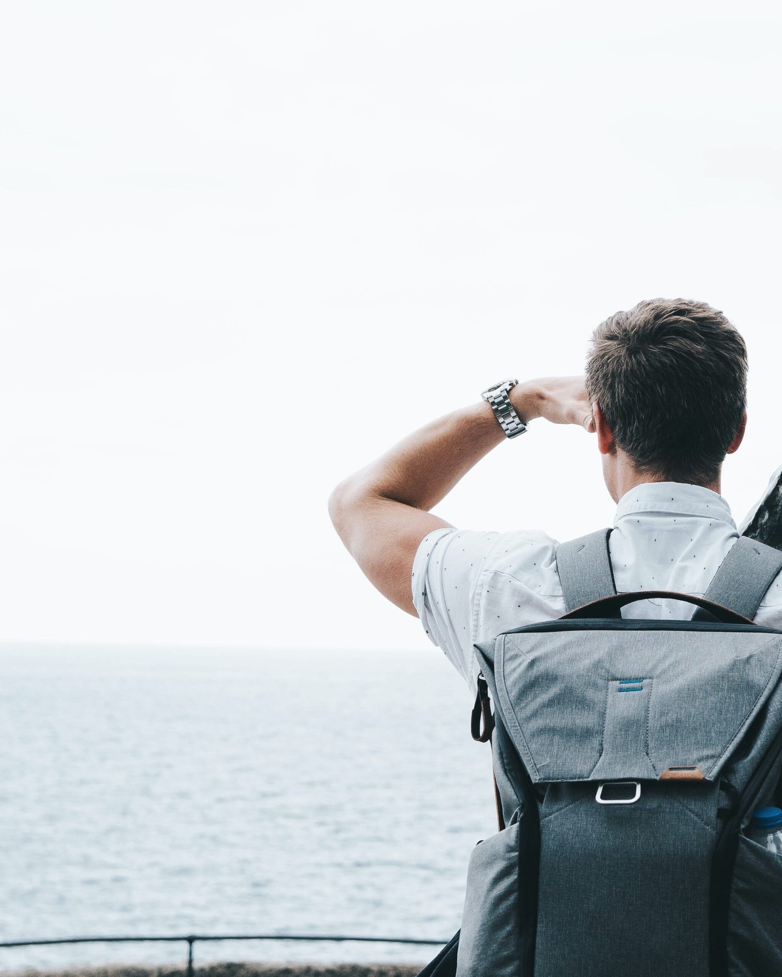 a man with a backpack looking out at the ocean