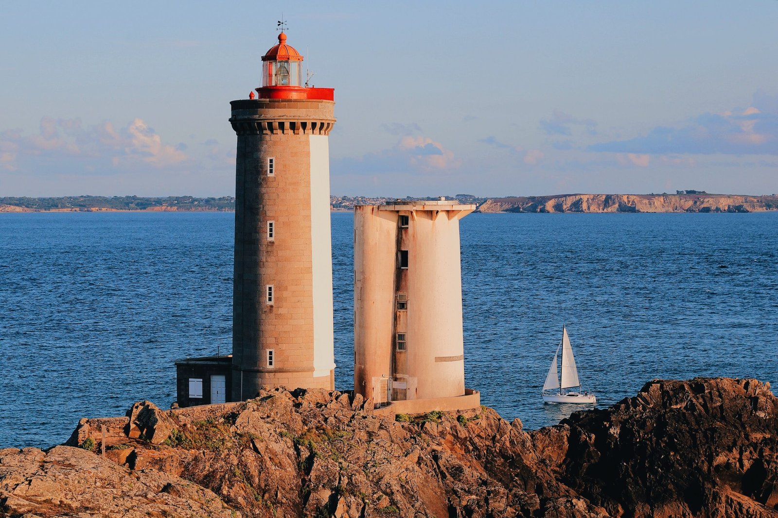 brown and white lighthouse across white sailboat