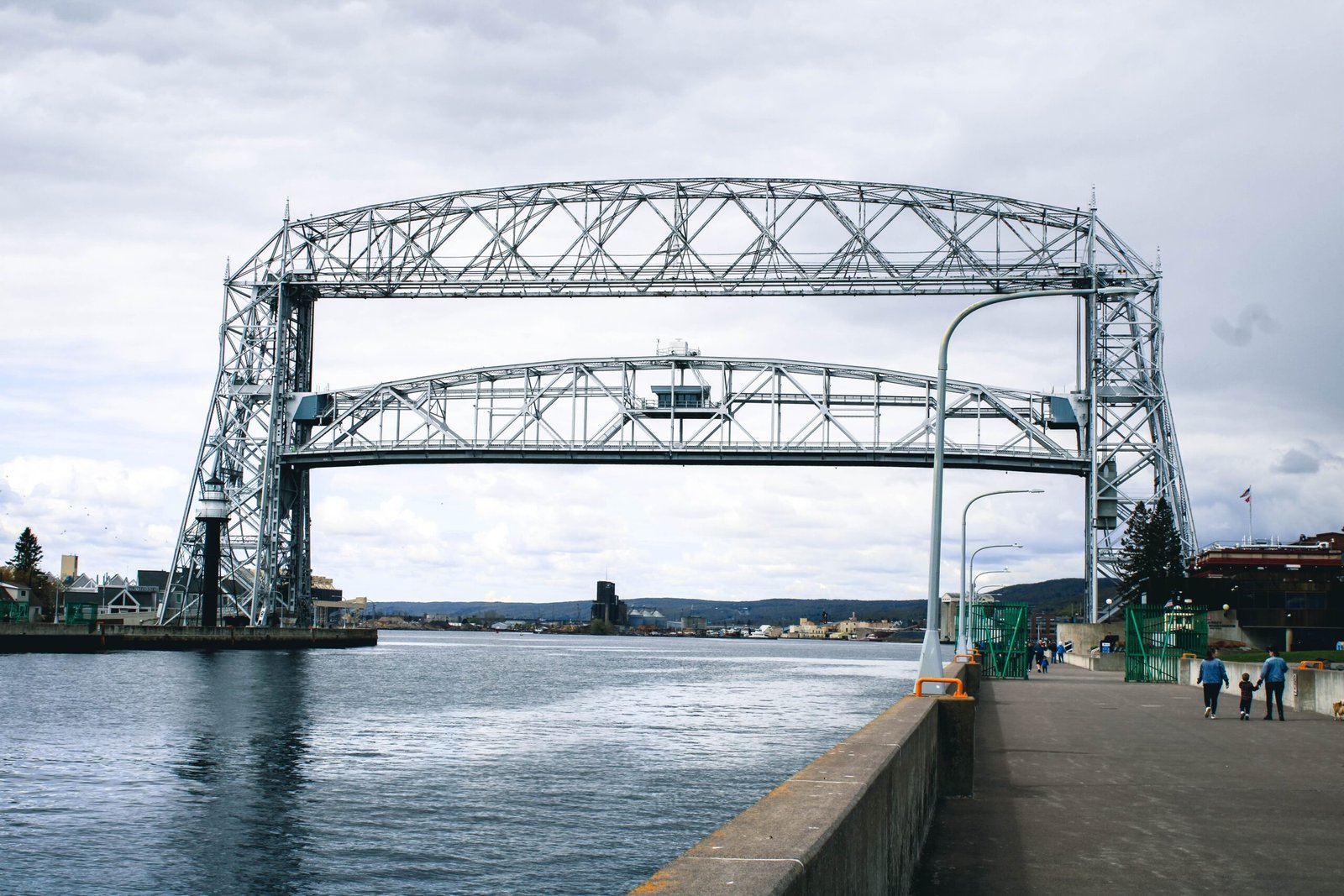 gray metal bridge over river under white sky during daytime