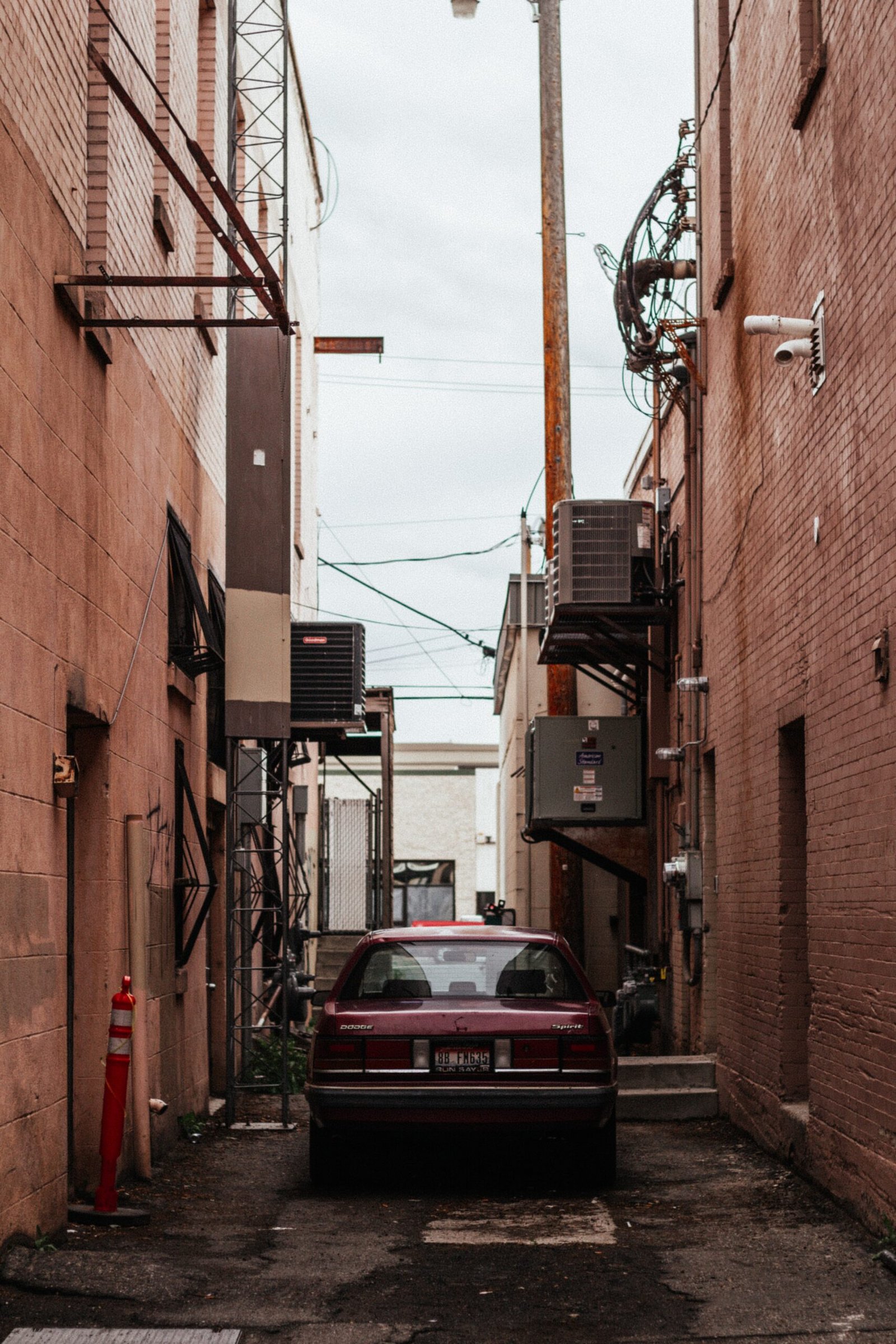 red car parked beside brown building during daytime