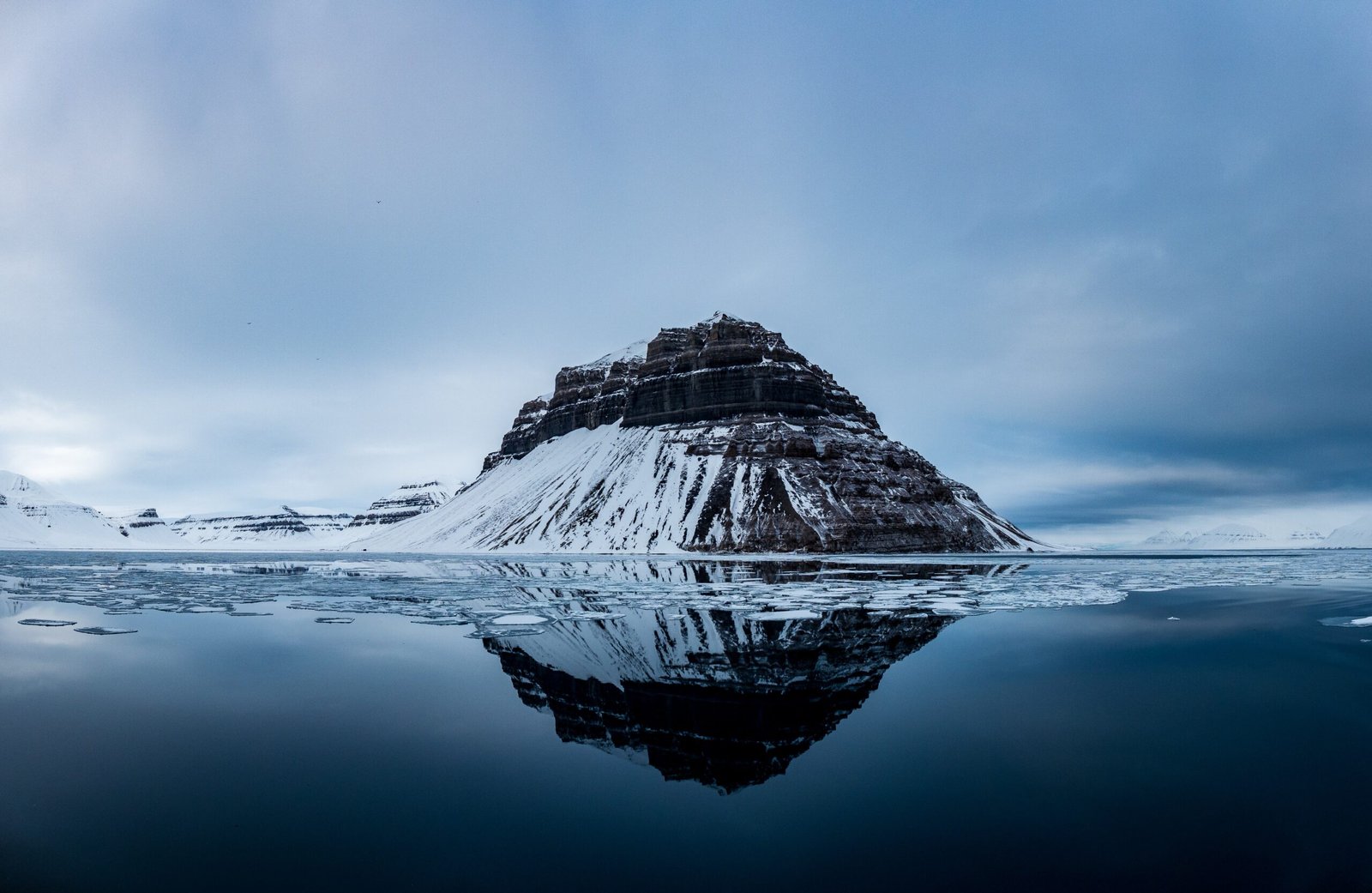 snow covered mountain near body of water